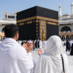 Pasangan jamaah umroh berdoa menghadap Ka'bah di Masjidil Haram dengan suasana ramai dan penuh kekhusyukan